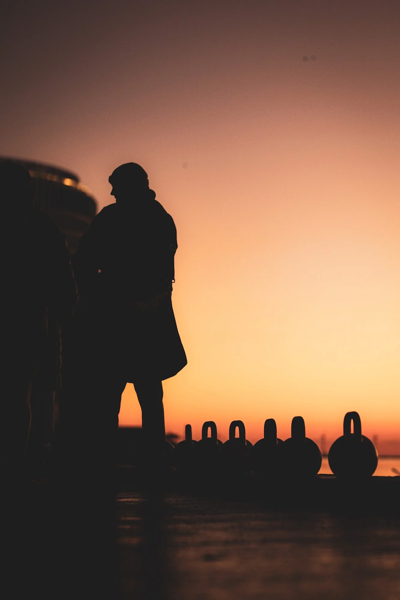Silhouet med kettlebells ved solnedgang